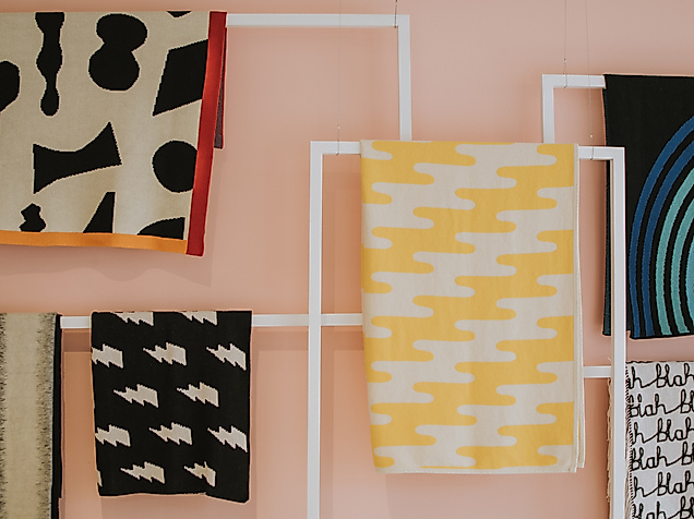 Dekorative Stoffbahnen mit bunten Mustern an einer rosa Wand in einem Hamburger Designladen