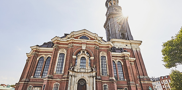 Frontansicht der barocken Kirche St. Michaelis mit Turm und Sonnenlicht in Hamburg.