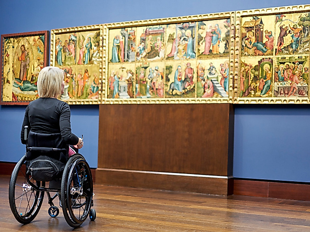 Rollstuhlfahrerin betrachtet ein mehrteiliges historisches Gemälde in der barrierefreien Hamburger Kunsthalle.