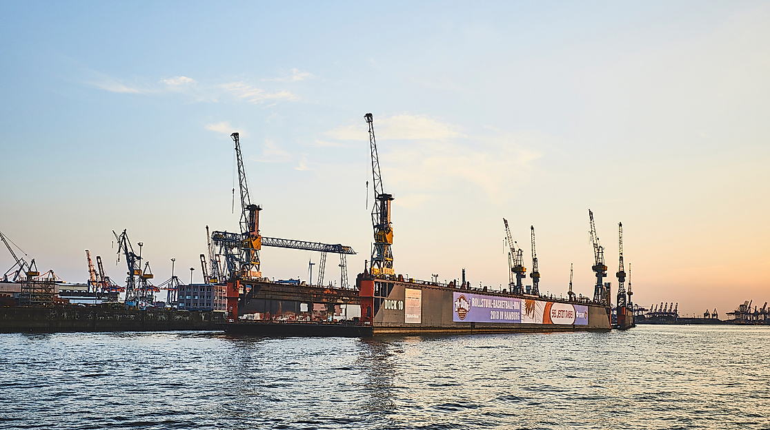 Hafendocks im Hamburger Hafen bei Sonnenuntergang mit Containerschiffen und Verladekränen am Wasser