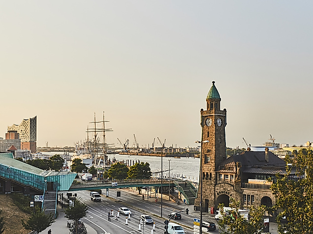 Sonnenaufgang über den Landungsbrücken mit Uhrturm, Elbphilharmonie und ruhiger Elbe im Morgenlicht