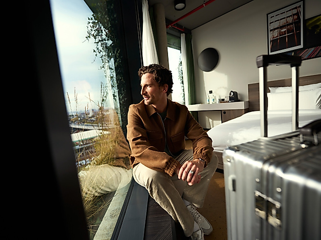 Mann blickt aus dem Fenster eines Hotelzimmers