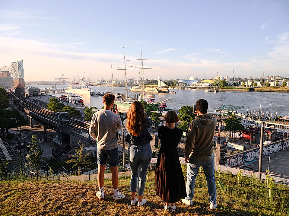 Vier Freunde schauen auf den Hamburger Hafen bei Sonnenaufgang
