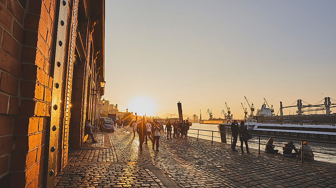 Sonnenaufgang am Hamburger Fischmarkt mit Lichtreflexen auf Backsteinfassade und Blick auf den Hafen