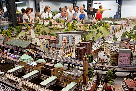 Besucher:innen bestaunen detailreiche Modelllandschaften mit Zügen und Stadtszenen im Miniatur Wunderland Hamburg