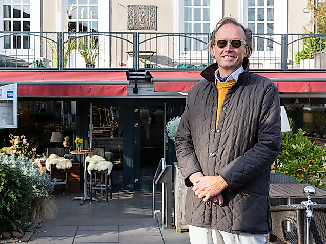 Andre Hallier mit Sonnenbrille vor Restaurantterrasse in Hamburg bei Sonnenschein