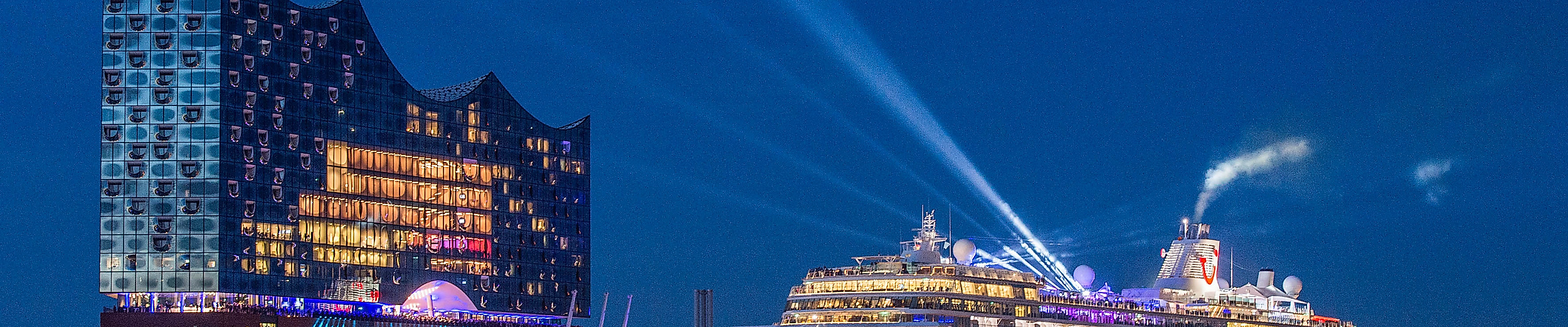 Beleuchtete Mein Schiff 6 bei nächtlicher Taufe vor der Elbphilharmonie mit Lichtshow im Hamburger Hafen