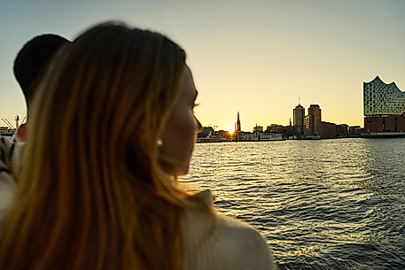 Zwei Personen im Bildanschnitt mit Blick auf die Elbphilharmonie im Hintergrund