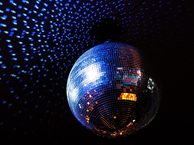 Spiegelkugel im Club wirft blaue und orange Lichtpunkte auf die dunkle Umgebung