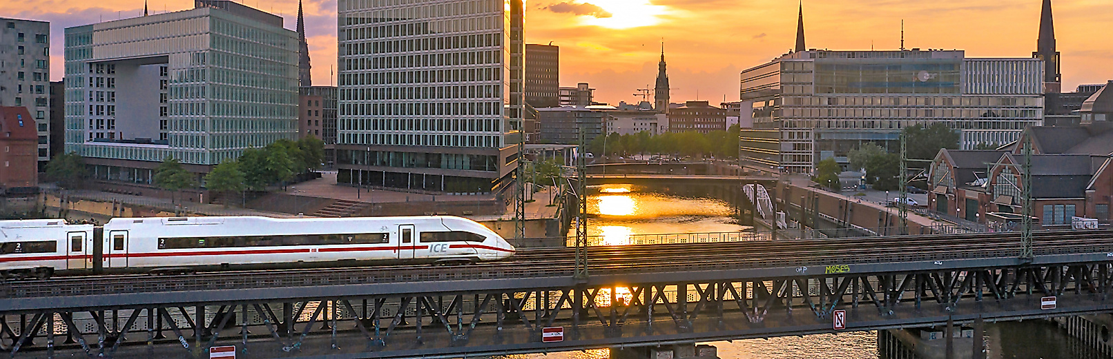 Einfahrender ICE bei Sonnenuntergang, im Hintergrund die Speicherstadt