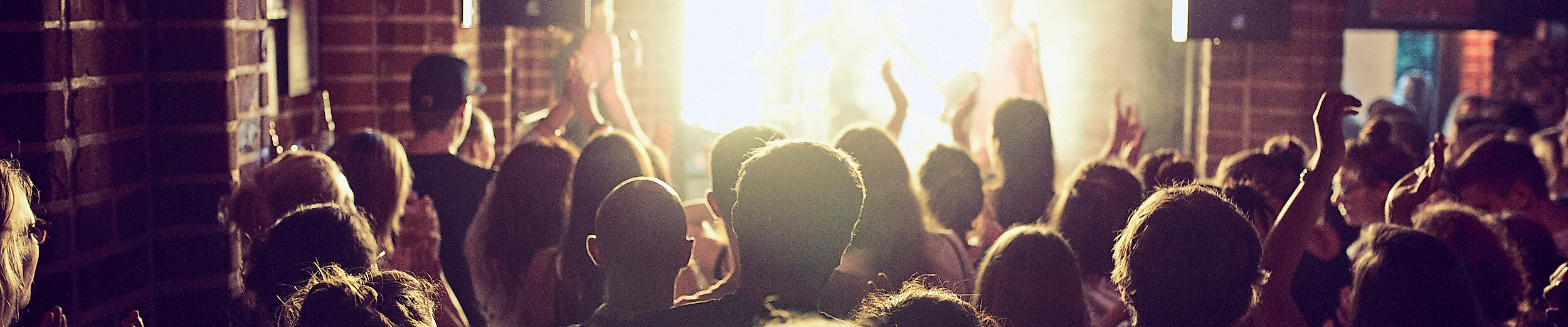Konzertbesucher feiern vor beleuchteter Bühne im Club „Freundlich und Kompetent“ in Hamburg