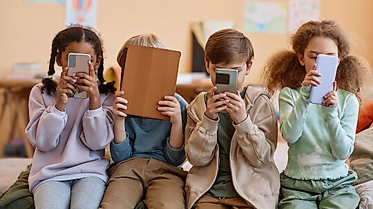 Group of young children holding smartphones and hiding faces, gen Alpha