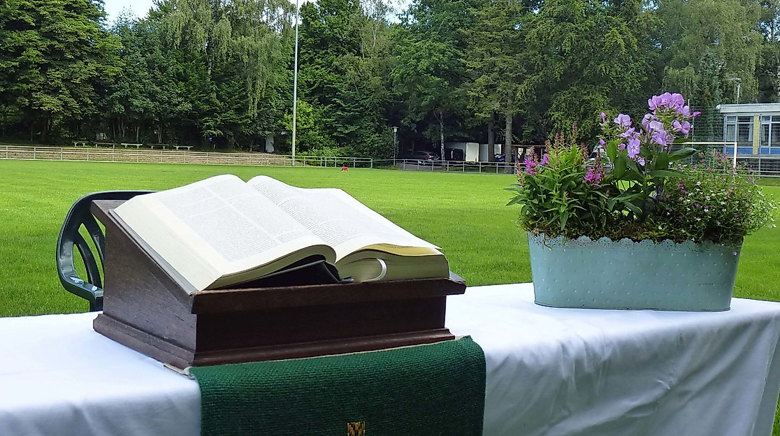 Aufgeschlagene Bibel und Blumenkorb auf einem Altar auf dem Fußballfeld