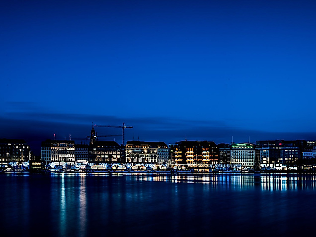 Beleuchtete Binnenalster mit Jungfernstieg und Spiegelungen im Wasser unter klarem Nachthimmel