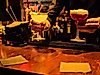Zwei Cocktails werden an einer Bar bei warmem Licht serviert, daneben Gläser und Barutensilien