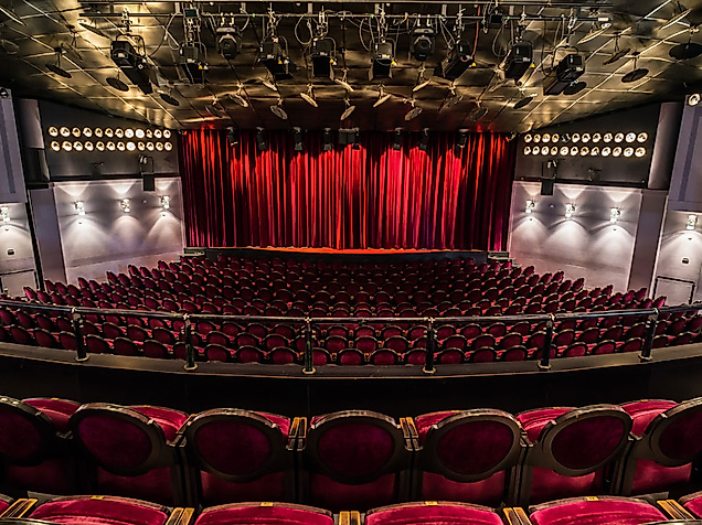 Blick in den Theatersaal des Winterhuder Fährhauses in Hamburg mit roten Samtsesseln und geschlossenem Vorhang