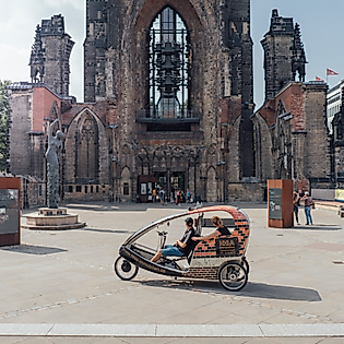 Rikscha mit Fahrgästen vor der Ruine der St.-Nikolai-Kirche im Zentrum von Hamburg