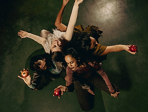 A group of people are standing close together in a circle. They are holding a fruit in their hands.