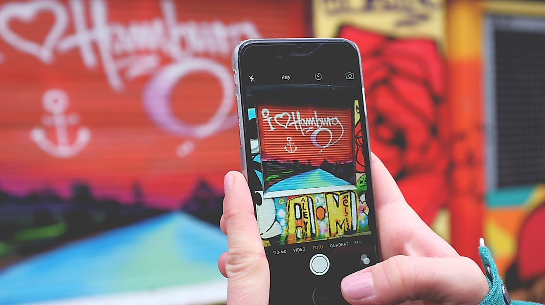 Smartphone fotografiert buntes Hamburg-Graffiti, Symbol für Social Media und Influencer-Kommunikation