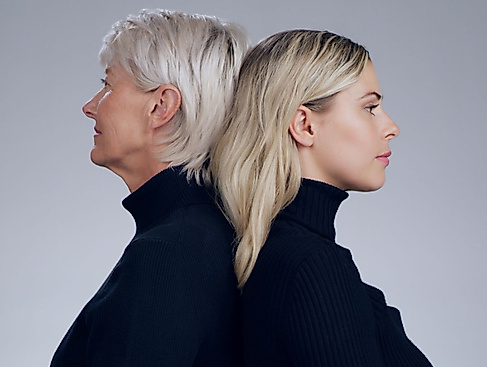 Eine ältere Frau und eine jüngere Frau die Rücken-an-Rücken stehen