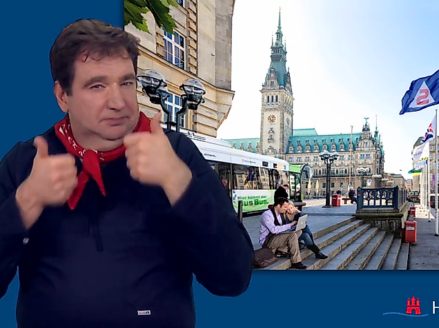 Man signing in International Sign in front of Hamburg City Hall about public transport.