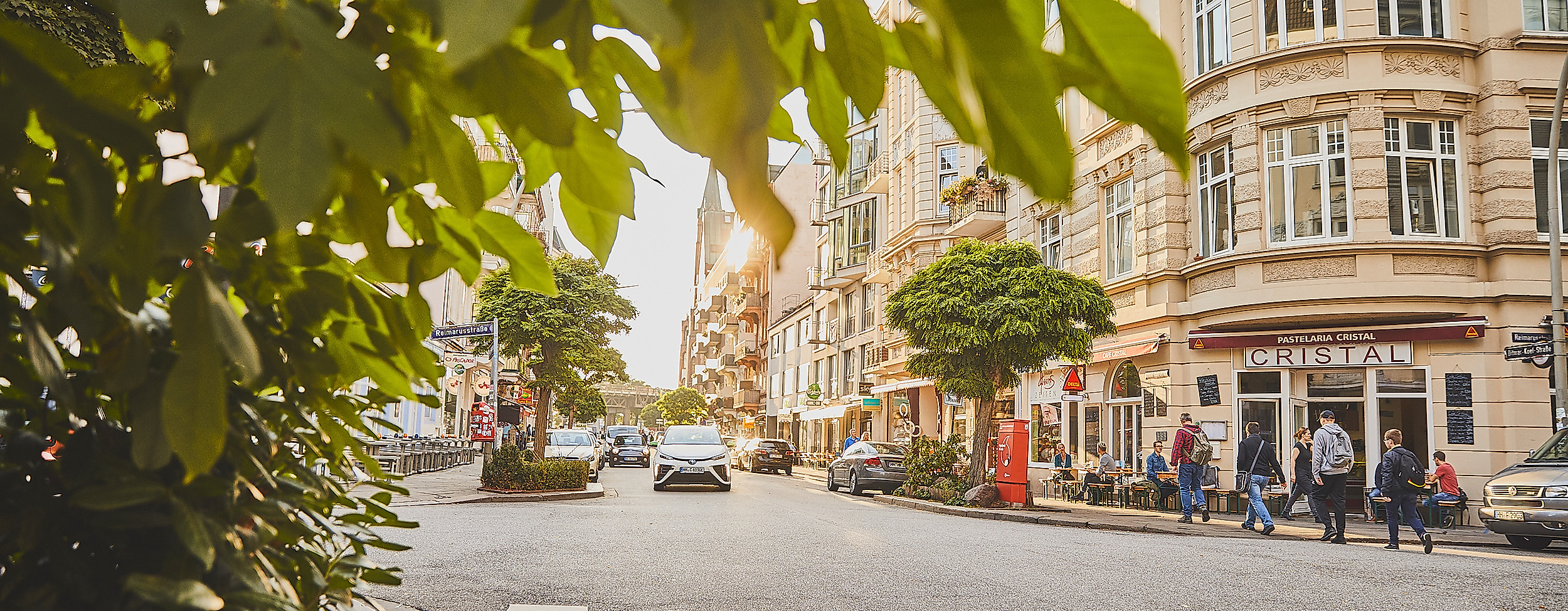 Belebte Straßenszene im Portugiesenviertel mit Restaurants und Altbaufassaden an einem sonnigen Tag