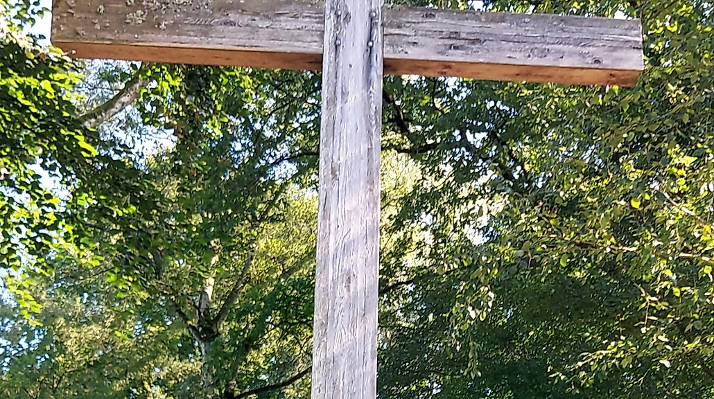 Holzkreuz vor Bäumen