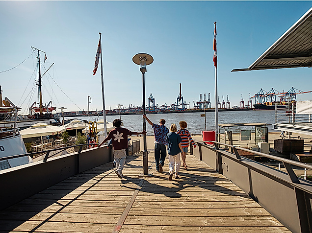 Gruppe junger Menschen läuft zur Elbe in Oevelgoenne in Hamburg