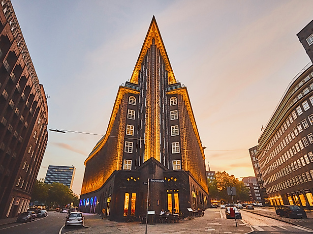 Spitz zulaufende Front des beleuchteten Chilehauses in Hamburg bei Sonnenuntergang
