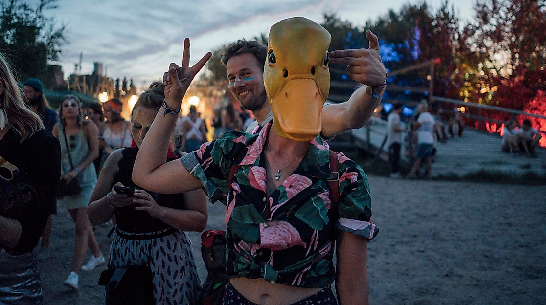 Festivalbesucher:innen in ausgefallenen Outfits und Vogelmaske feiern beim Vogelball