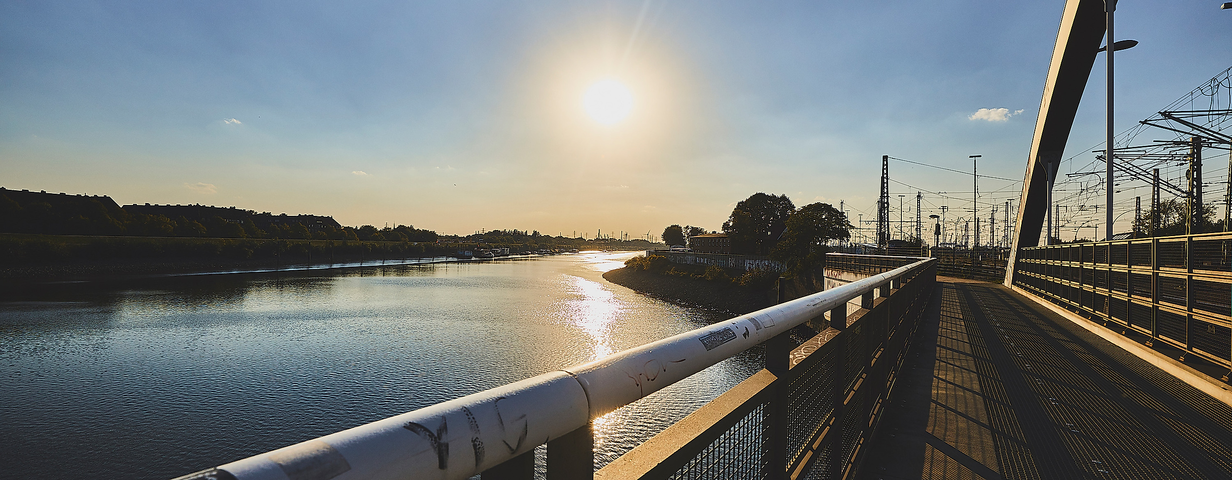 Sonnenuntergang über dem Veddeler Spreehafen, gesehen von einer Brücke mit Blick auf Wasser und Ufer