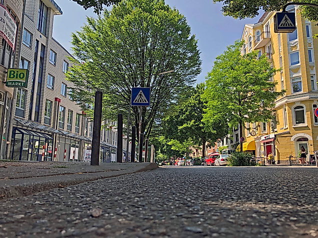Grüne Bäume säumen die Gertigstraße in Hamburg, umgeben von Altbauten, Cafés und kleinen Geschäften