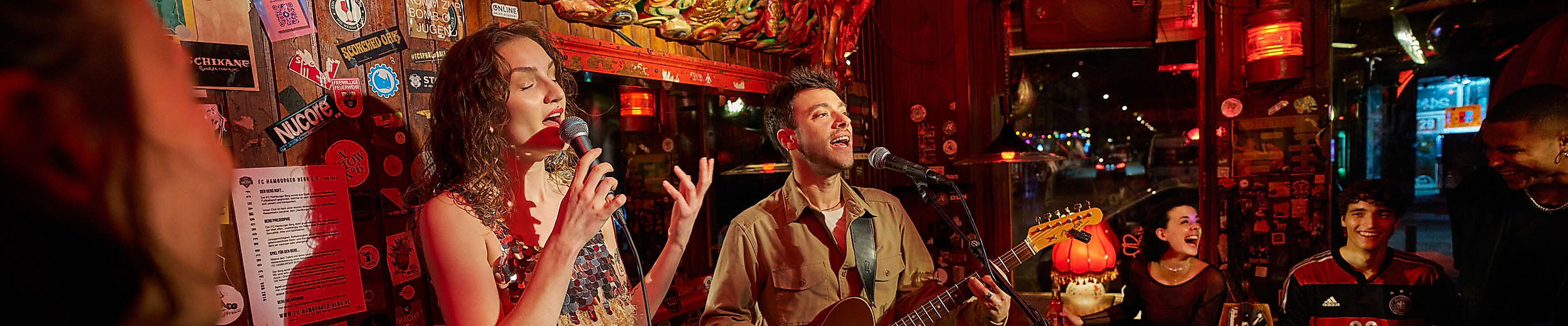 A singer and a guitarist on a quaint pub stage.