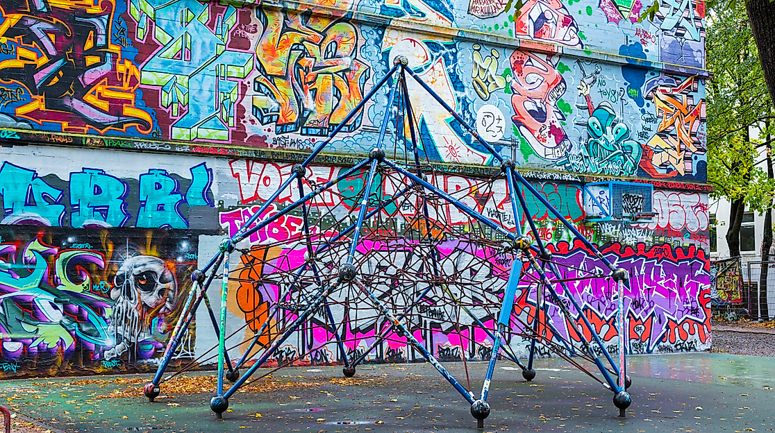 Klettergerüst vor bunt besprühter Wand im Hamburger Schanzenviertel mit Streetart und herbstlich gefärbtem Laub