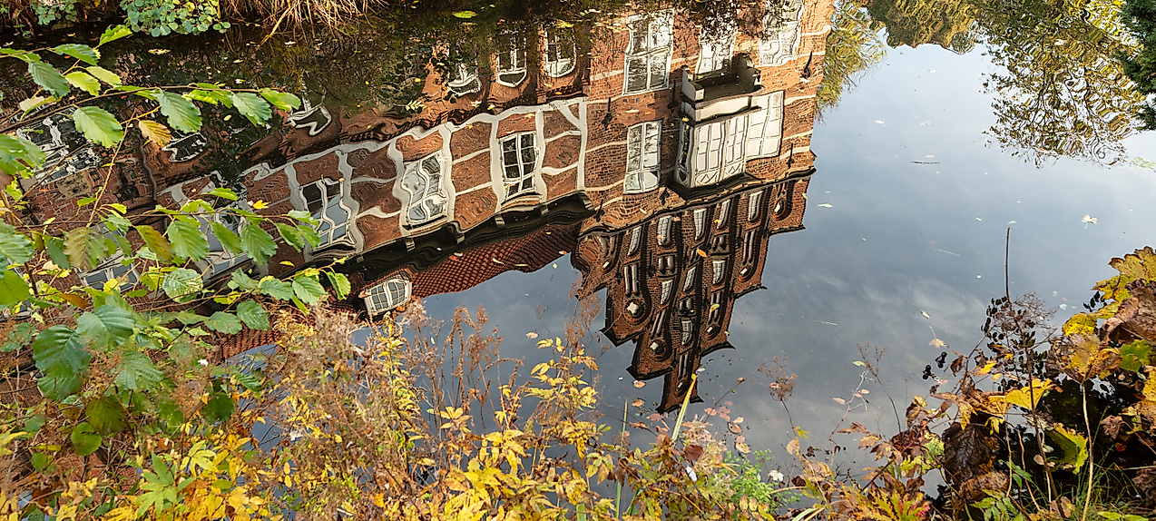 Spiegelung des Bergedorfer Schlosses im Wassergraben, umrahmt von herbstlicher Vegetation in Hamburg-Bergedorf