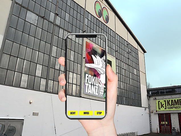 Smartphone zeigt App Kampnagel to go vor dem Gebäude von Kampnagel Hamburg mit Industriefassade