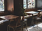 Helles Café mit Holztischen, Stühlen und Fensterplätzen, einladend für eine entspannte Auszeit beim Shoppen.
