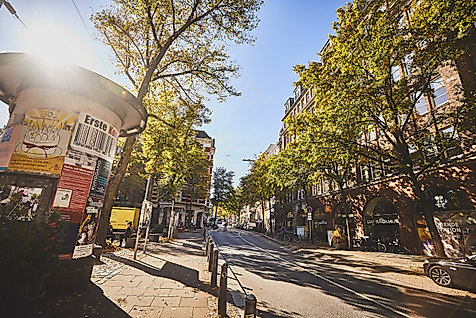 Belebte Lange Reihe in Hamburg-St. Georg bei Sonnenschein mit Passant:innen, Bäumen und Caféterrassen