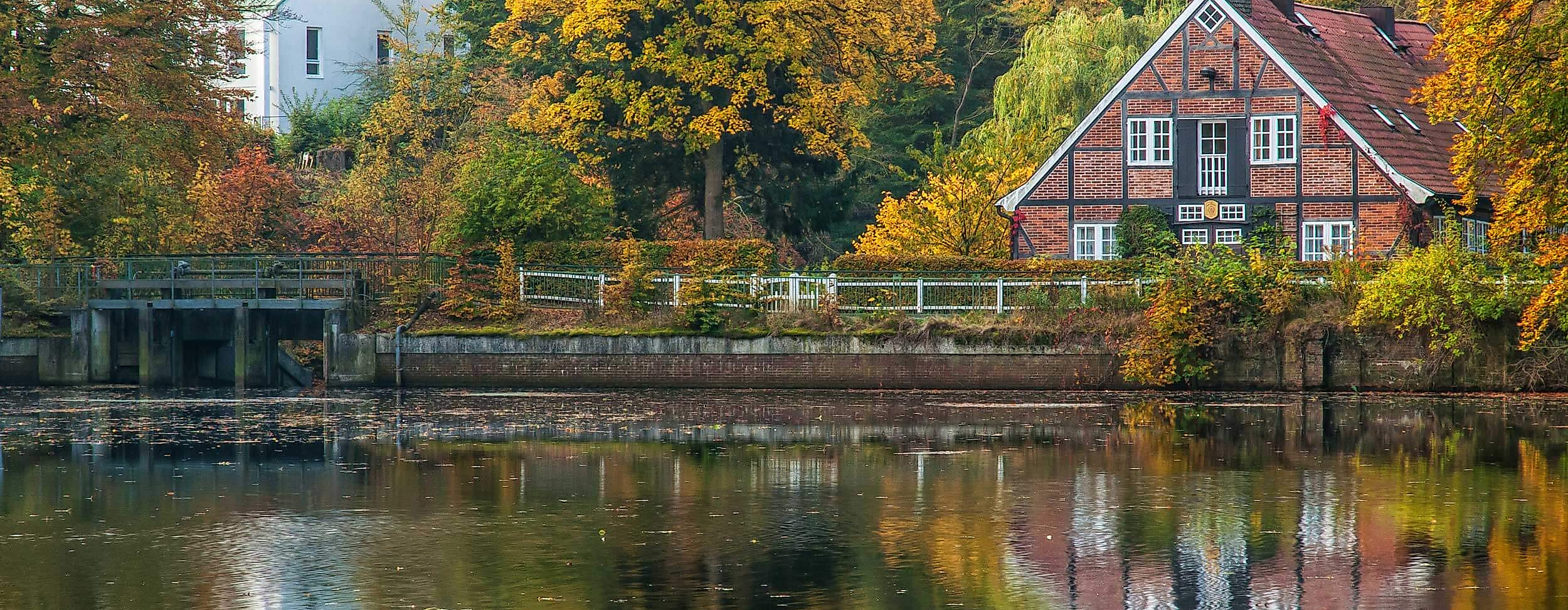 Fachwerkhaus am Teich im Duvenstedter Brook, umgeben von buntem Herbstlaub und Spiegelung im Wasser