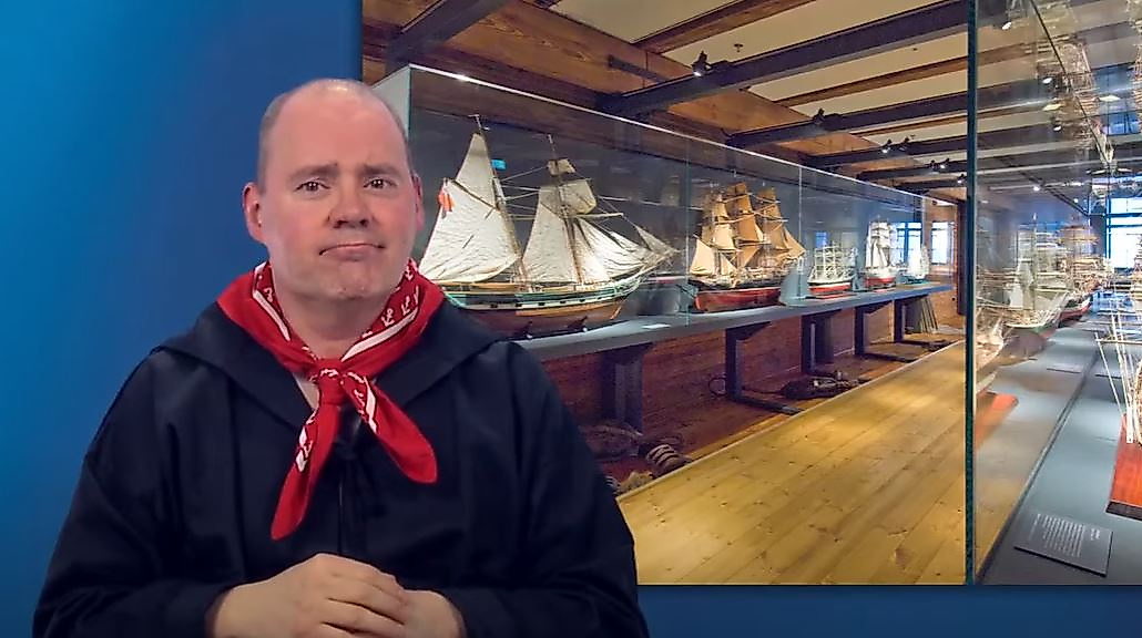Mann gebärdet vor Ausstellungsraum mit maritimen Objekten – barrierefreie Infos zu Kultur in Hamburg.