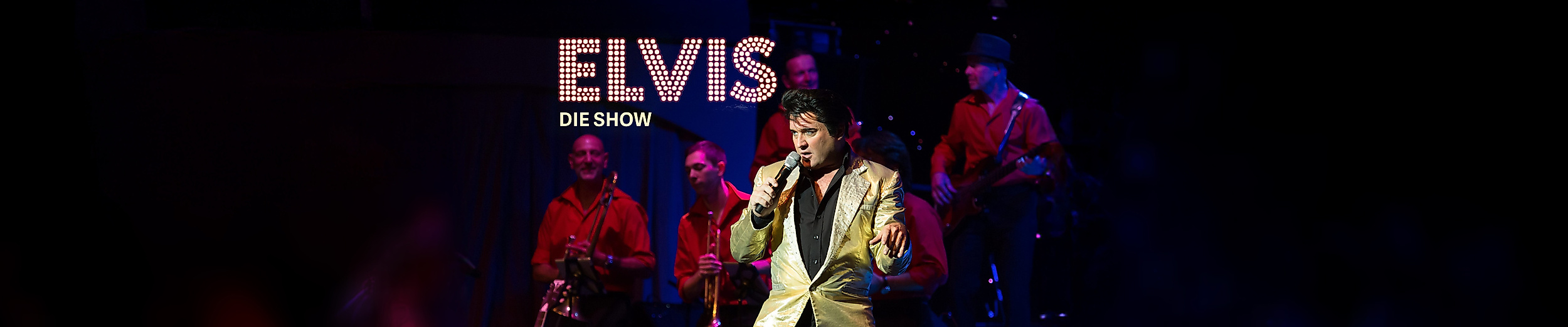 Elvis Darsteller auf der Bühne mit Band im Hintergrund