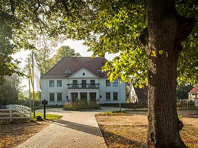 Herrenhaus Gut Vorbeck bei WINSTONgolf, umgeben von Bäumen und Abendlicht in der Golfregion Hamburg.