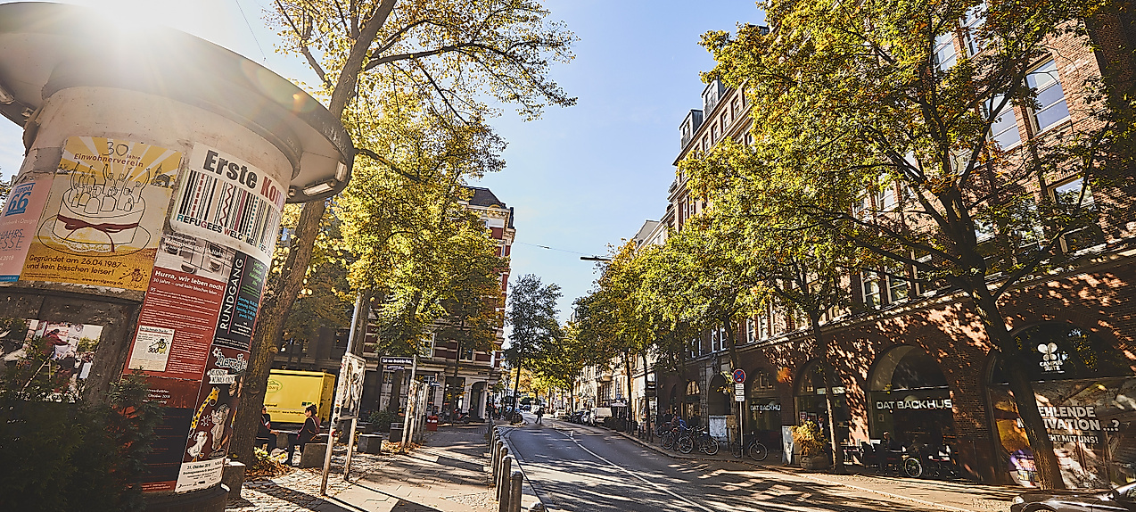 Belebte Lange Reihe in Hamburg-St. Georg bei Sonnenschein mit Passant:innen, Bäumen und Caféterrassen