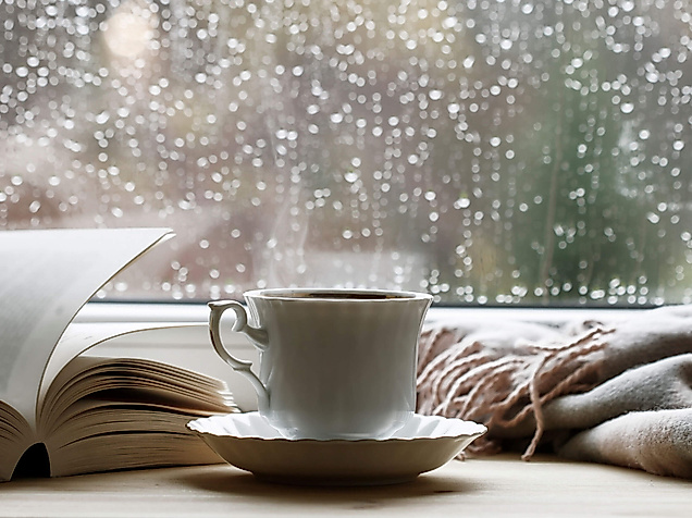 Gemütliche Tasse Tee vor verregneter Fensterscheibe