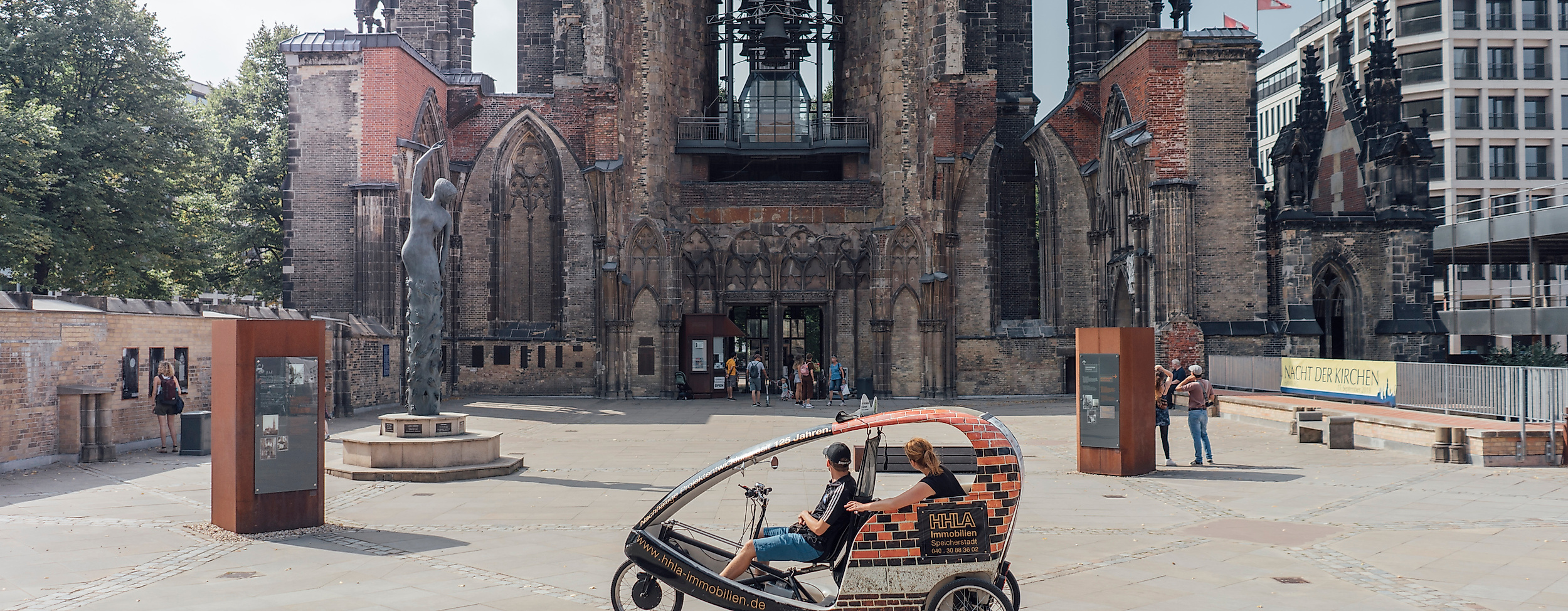 Rikscha mit Fahrgästen vor der Ruine der St.-Nikolai-Kirche im Zentrum von Hamburg