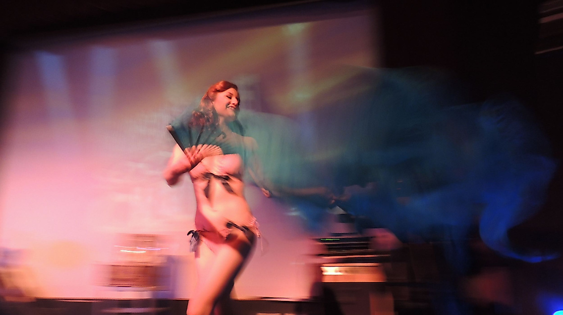 Burlesque-Performance mit Federfächern auf Bühne im Scheinwerferlicht einer Hamburger Veranstaltung
